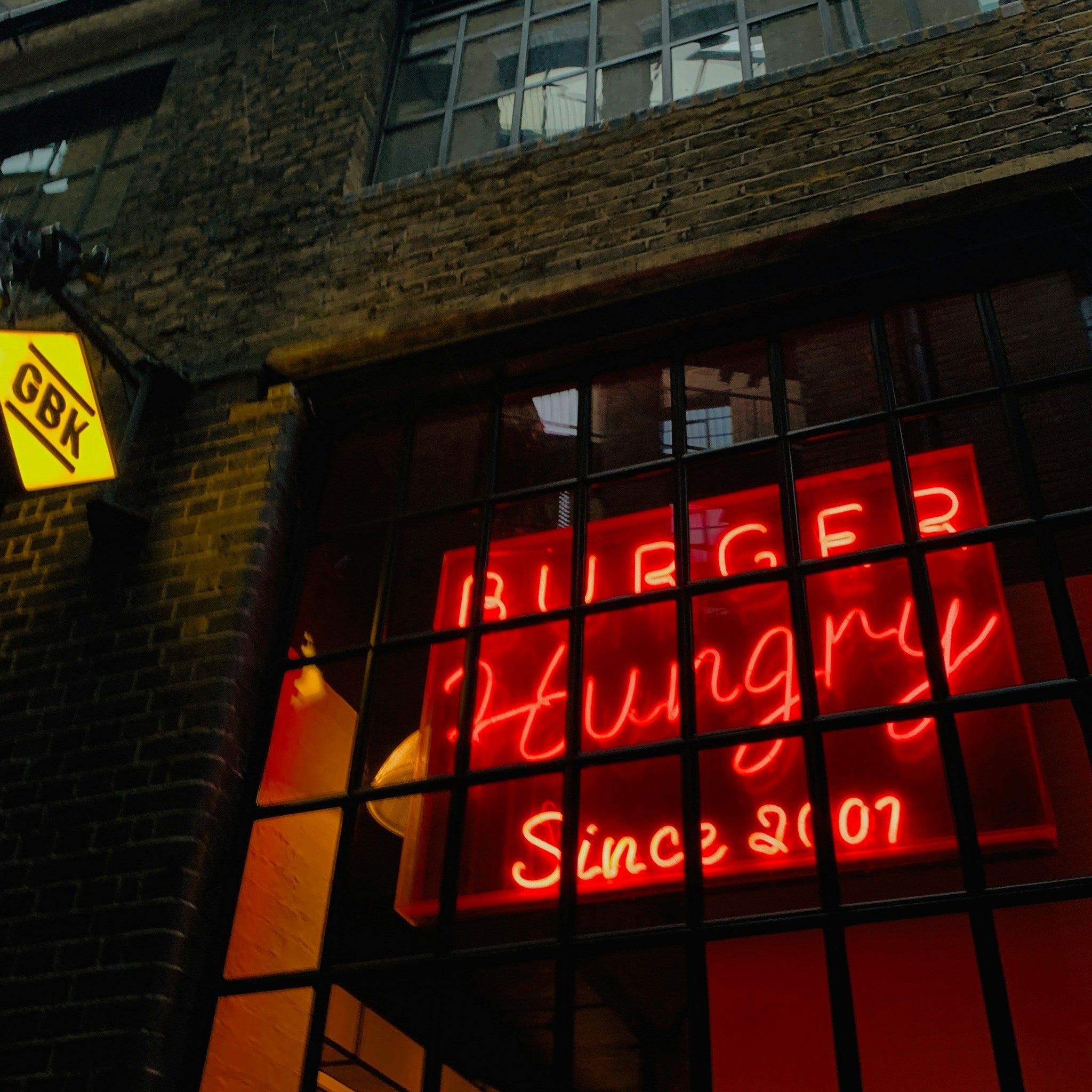 Neon sign in a window of a building with 'Burger Hungry Since 2007' text.