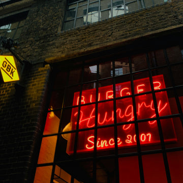 Neon sign in a window of a building with 'Burger Hungry Since 2007' text.